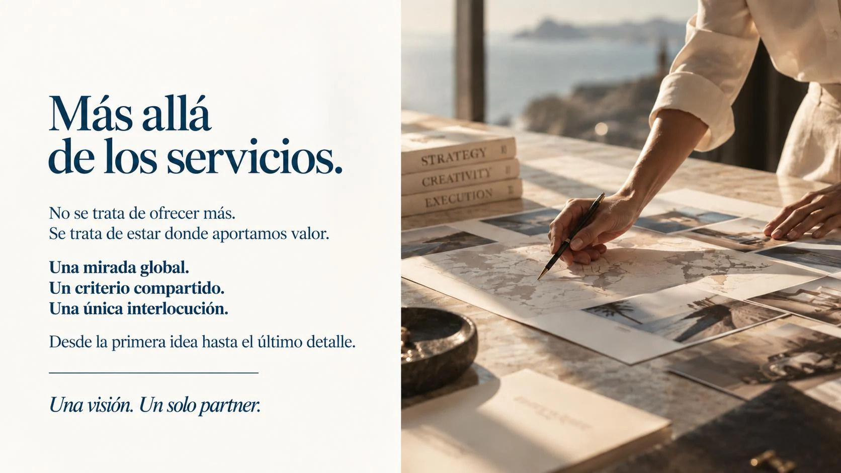 Mesa de trabajo con mapas, fotografías y libros de estrategia, creatividad y ejecución, con el mar al fondo.